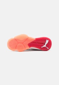 Suola di scarpe sportive con un design in gomma bianca e rosa, caratterizzata da un motivo a zigzag e un piccolo logo sul tallone in bianco a contrasto.