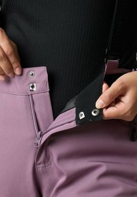 Lichtpaarse broek met een rits- en drukknoopsluiting. Het materiaal lijkt glad met een matte afwerking en toont een contrasterende zwarte binnenvoering.