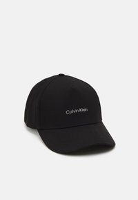 Svart basebollkeps i tyg med en rundad skärm, som har en vit broderad "Calvin Klein"-logotyp på framsidan.