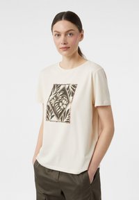 Kremowa bawełniana koszulka z krótkim rękawem i okrągłym dekoltem, z brązowym kwiatowym nadrukiem w kształcie diamentu na przodzie.