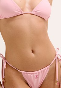 Ensemble bikini rose comprenant un haut en triangle avec des fines bretelles et un bas taille basse. Le tissu est lisse, avec un petit logo sur le côté.