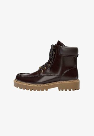 Stivale in pelle marrone con un design strutturato, punta rotonda e suola in gomma spessa e testurizzata. Presenta occhielli in metallo e cuciture a contrasto.