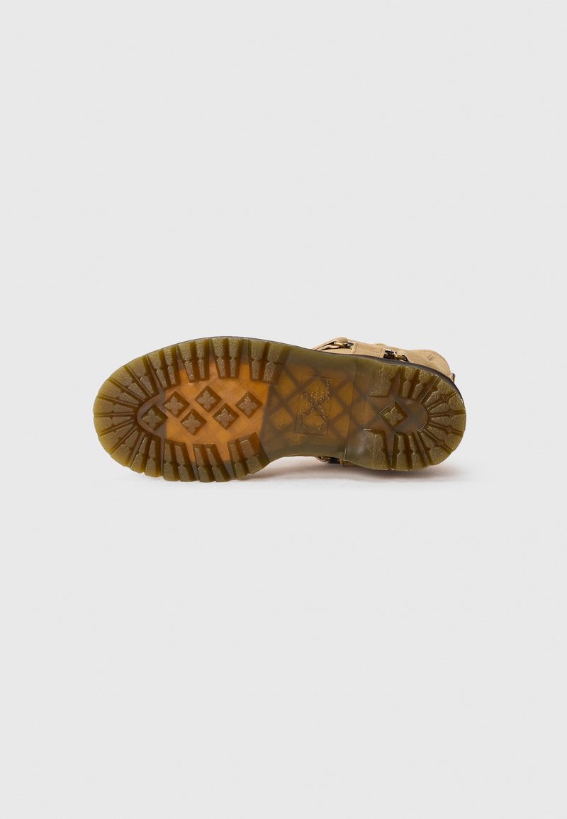Semelle de bottes de randonnée marron avec un motif de bande de roulement robuste. Fabriquée en caoutchouc, elle présente de profonds cannelures pour une meilleure adhérence et un léger talon.