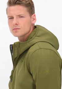 Olivovo zelená sivá bunda s kapucňou, so zipsom vpredu, jemnou vnútornou podšívkou a vyšitými detailmi na rukáve. Hladká tkanina s elegantným dizajnom.