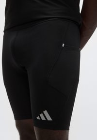 Μαύρα σφιχτά σορτς με υφασμένο τσέπη στο πλάι· διαθέτουν γκρι λογότυπα και απαλό ύφασμα. Σχεδιασμένα για απόδοση και άνεση.