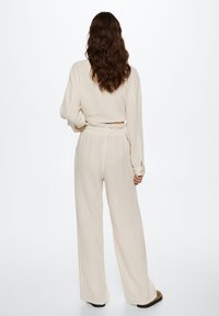 Ensemble en ivoire, texturé, composé d'un haut court à manches longues et d'un pantalon large à taille haute, présentant une coupe décontractée et une taille élastique.