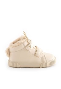 Sneaker montante en cuir beige avec doublure moelleuse, deux sangles réglables et semelle en caoutchouc texturée pour l'adhérence. Fermeture éclair sur le côté pour un enfilage facile.
