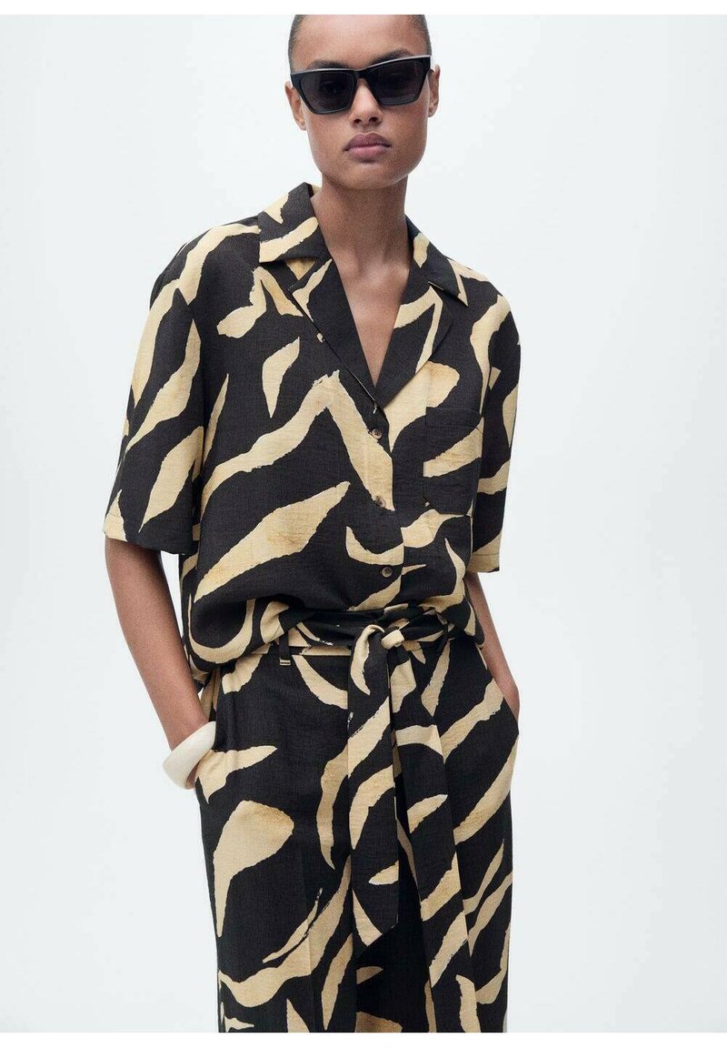 Chemise à manches courtes et pantalon assorti en imprimé abstrait noir et beige. Tissu léger avec une coupe décontractée, doté d'une ceinture à la taille.