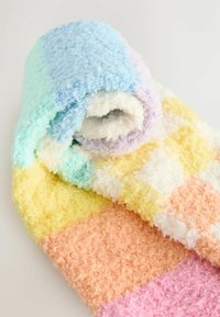 Farbenfrohe, flauschige Decke, aufgerollt und mit Pastellabschnitten in Blau, Grün, Lila, Gelb, Orange und Pink versehen. Weiche, strukturierte Oberfläche.