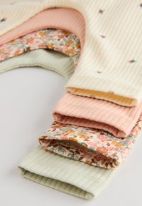 Satz von vier Strickstoffstücken: gerippt in Gelb, Pink und Grün, mit einem Stück in floralem Muster. Weiche Textur, Pastellfarben, geschichtete Anordnung.