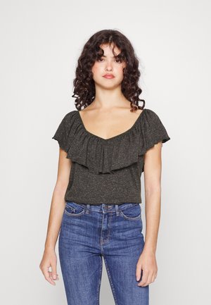 Top cinza escuro com mangas bufantes, decote em forma de barco e textura suave. Usado com jeans azuis, apresentando detalhes sutis de costura.