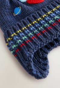 Bonnet en tricot pour enfant de couleur bleu marine, avec des rayures multicolores et des motifs de planètes brodés. La texture est épaisse et chaude.