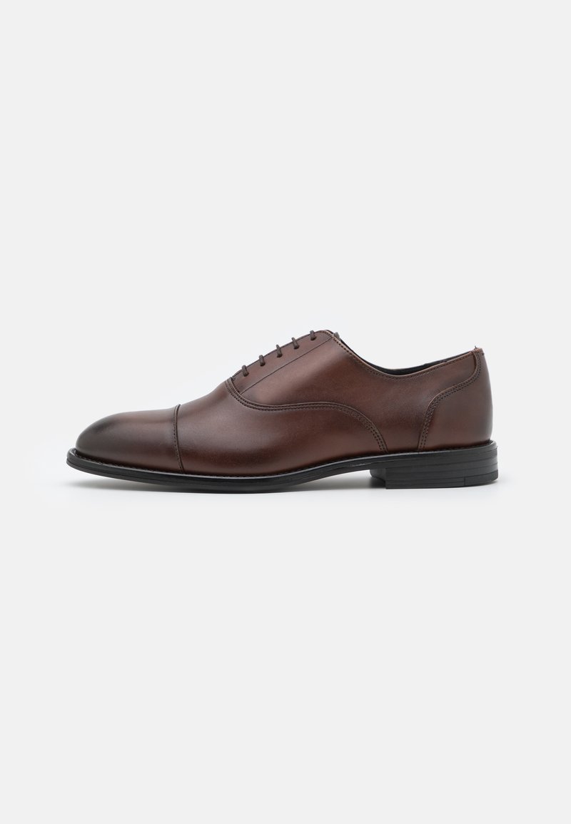 Brown leather dress shoe with a smooth finish, cap toe design, and subtle stitching details. Features a black rubber sole and lace-up closure.