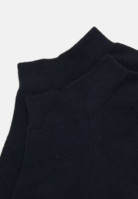 Calcetines de algodón negros con un puño texturizado y acanalado y un cuerpo suave. Presentan un diseño sin costuras y un color sólido en todo su recorrido.