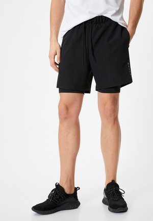 Sorte atletiske shorts med elastisk talje og snor. Har en kontrasterende inderside og buede sidelommer.