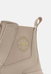 Tana Converse čizma s mješavinom platna i kože, zaobljenim vrhom, elastičnim bočnim panelima i okruglim logotipom s zvijezdom.