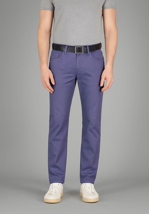 Schmale lila Hose aus Baumwolle mit Taschen und einem Gürtel. Kombiniert mit weißen Turnschuhen und einem grauen T-Shirt für einen lässigen Look.