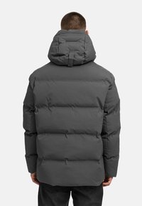 Pilkas puferis su aukštu apykakle, horizontaliais siuvinėjimo skyriumi ir reguliuojama kapuce su kilpele saugiam užsegimui.