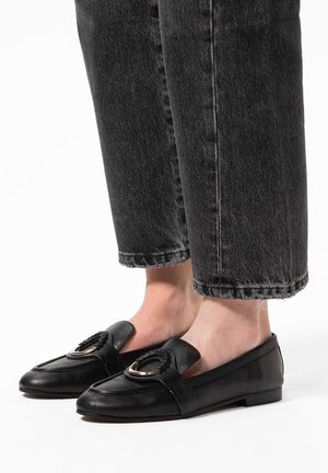 Zwarte leren loafers met een afgeronde neus, voorzien van een decoratieve gevlochten accent en gouden hardware. Plat, laag profiel met open zijkanten.