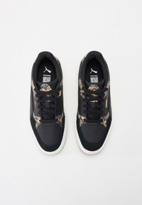 Black sneakers with a textured snake print design, suede accents, and white rubber soles. Laced with black shoelaces and logo on the tongue.
