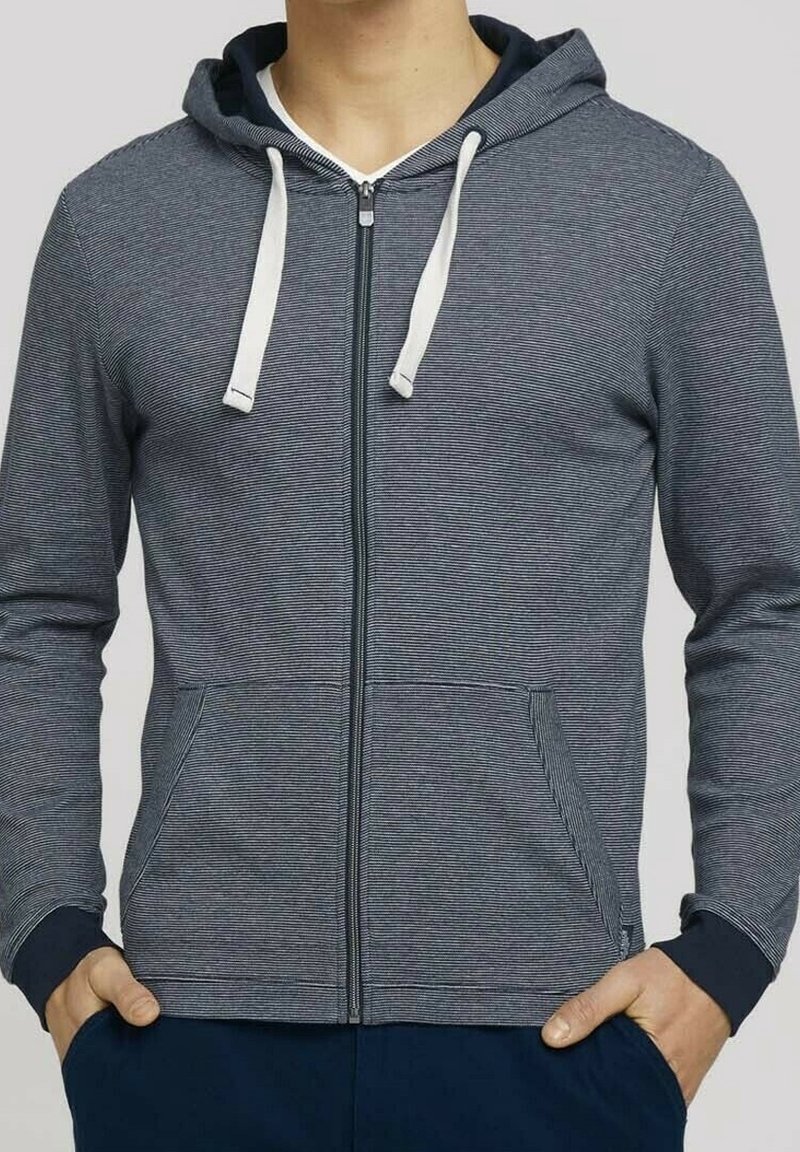 Felpa con zip di colore grigio scuro, con lacci bianchi, polsini a coste, due tasche e un sottile motivo a righe orizzontali. Tessuto morbido.