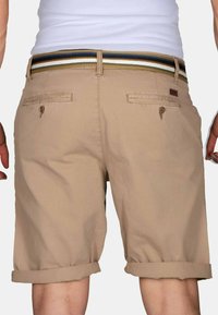 Khaki shorts with a rolled hem, featuring two back pockets, a woven multicolored belt, and a leather brand tag on the waistband.