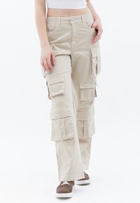Beige Cargo kalhoty s několika kapsami, volným střihem a zapínáním na knoflík. Vyrobeny z lehkého materiálu s hladkým povrchem.