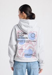 Sudadera gris con capucha ajustable, que presenta un gráfico colorido en la parte trasera, incluyendo texto y formas abstractas en rosa y azul.