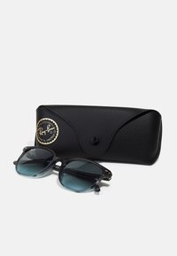 Ochelari de soare cu lentile gradient albastre, ramă din acetat negru, detalii metalice argintii, așezați lângă o husă din piele neagră cu logo.