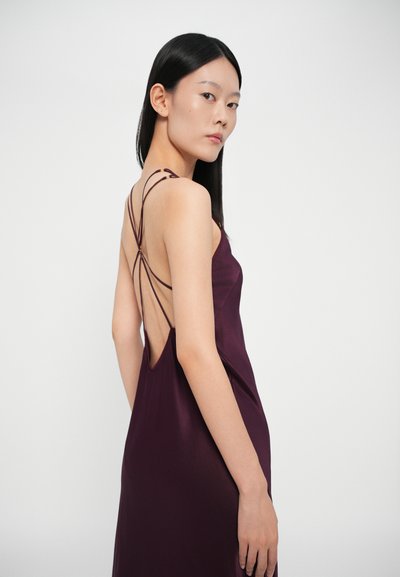 Vestido de cetim bordô com um decote profundo nas costas e alças entrelaçadas. Textura suave e design minimalista realçado por delicados detalhes de costura.