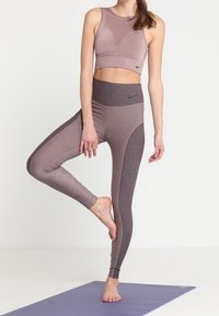 Lilla sports-bh og leggings sæt i tekstureret stof. Leggings har en høj talje og kontrastfarver i mauve og grå.