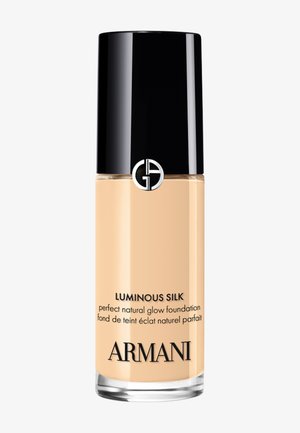 Botella de base de maquillaje Armani Luminous Silk con brillo natural, tapa negra y logo plateado sobre fondo blanco.