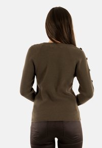 Maglione a coste marrone con maniche lunghe e bottoni decorativi sulla spalla. Design aderente, texture minimale e colore uniforme.