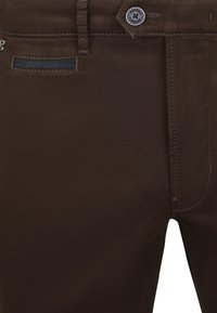 Bruine slim-fit broek van gladde stof; heeft een knoopsluiting, gestikte accenten en een klein detail van een achterzak.