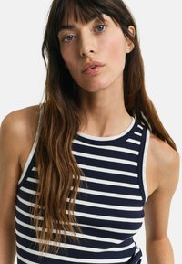 Marineblå og hvid stribet tank top med ribbet tekstur, der har en klassisk crew neckline og brede skulderstropper.