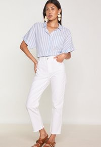 Light blue and white striped short-sleeve button-up shirt, paired with high-waisted white jeans and brown sandals. Large floral earrings.