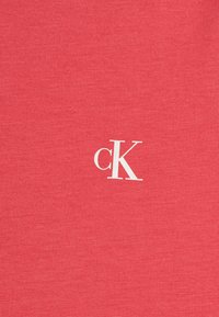 Kora t-krekls, kas izgatavots no kokvilnas, ar teksturētu virsmu un balto "cK" logo priekšpusē, centrāli izlīdzināts.