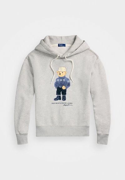 Siv hooded pulover iz mešanice bombaža, ki ima natisnjenega medveda v modrem puloverju z cvetličnim vzorcem. Ima kapuco z vrvico in rebraste manšete.