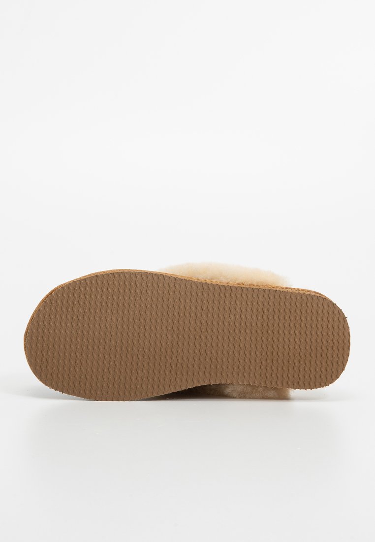 Bruine rubberen zool met een gestructureerd oppervlak, voorzien van een lichtbruine, fluffy bovenlaag, ontworpen voor comfort en warmte.