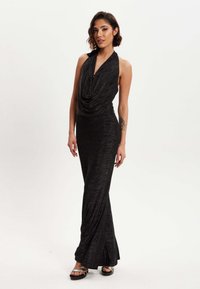 Black halterneck gown with draped bodice and flared skirt, made from a textured, shimmering fabric; features a button detail at the neckline.
