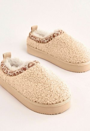 Beige Fleece gefütterte Hausschuhe mit einer strukturierten Oberfläche, Animal-Print-Besatz und einem flachen Profil. Sie verfügen über eine glatte, flache Sohle und eine Zuglasche hinten.