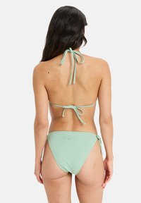 Mintgrön bikinitopp i halterneckdesign med justerbara band, låga byxor och en subtil logotyp på bakre delen. Slät textur.
