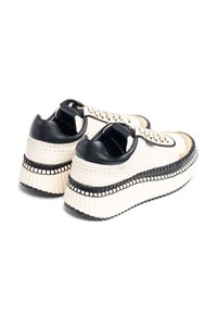 Sneaker platform spessi con tomaia in tela crema, dettagli in pelle nera e cuciture a contrasto. Suola spessa e texturizzata con battistrada in gomma.