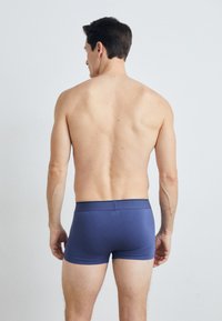 Men's fitted boxer briefs in navy blue, made from smooth fabric. Features a soft waistband and a minimalist design. View from the back.