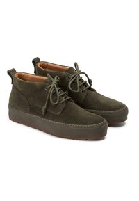 Bottines en suède vertes avec des orteils ronds, un laçage à l'avant et des semelles en caoutchouc marron. Présente une texture lisse et des détails de couture.