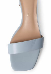 Sandalia de tacón azul claro con una correa suave que cruza el pie y una suela de plataforma sólida, con un sutil logo en relieve en la plantilla.