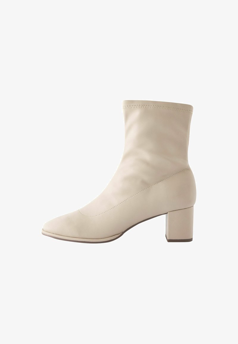 Beige ankle boot made of smooth leather, featuring a pointed toe and a square heel. Seamless design with minimal stitching detail.