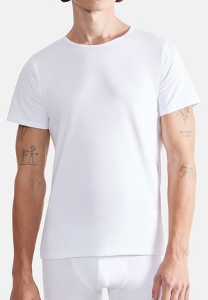 White cotton t-shirt with short sleeves, crew neckline, soft texture, and a fitted design. Features visible tattoos on both arms.