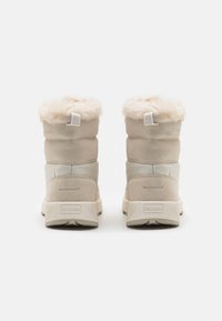 Beige waterproof boots with faux fur trim, smooth and textured materials, mid-calf height, and a sturdy rubber sole with logo accents.