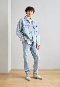 Light blue denim oversized jacket and jeans, paired with a white shirt and beige ankle boots. Simple, casual design with a relaxed fit.